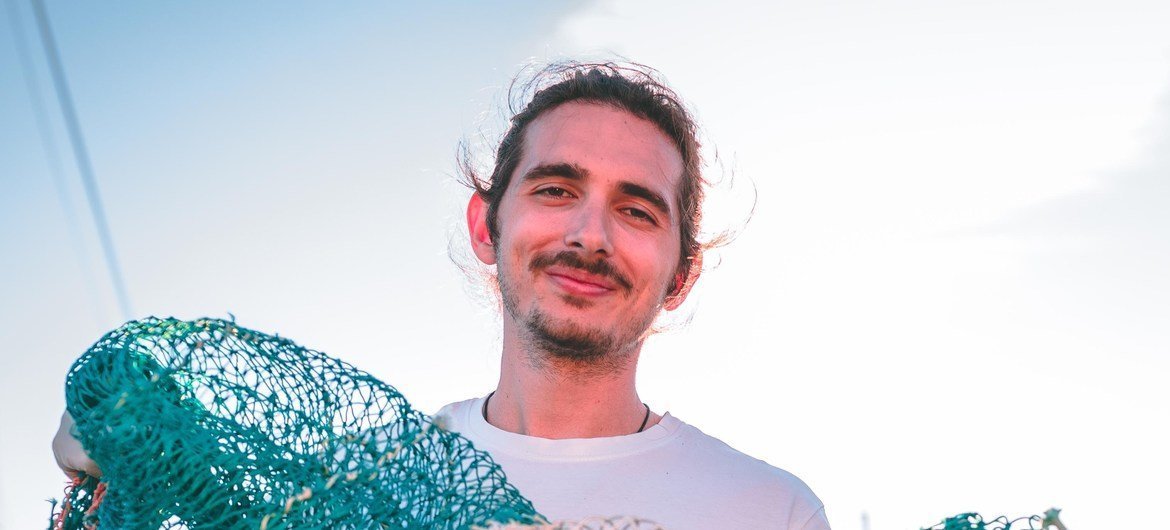 Greek man Lefteris Arapakis holds a large pile of discarded fishing nets in front of him.