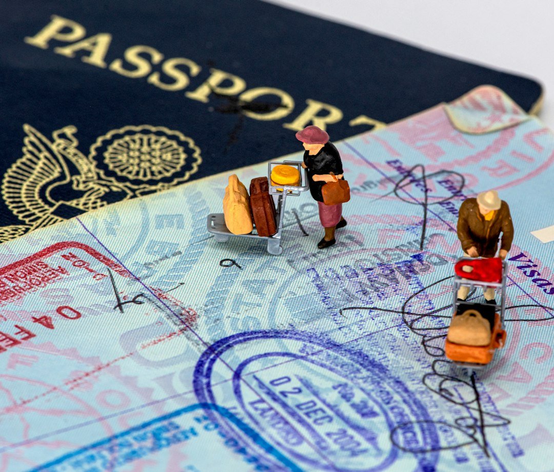 Miniature travellers with luggage on a passport; photo by mana5280 on Unsplash