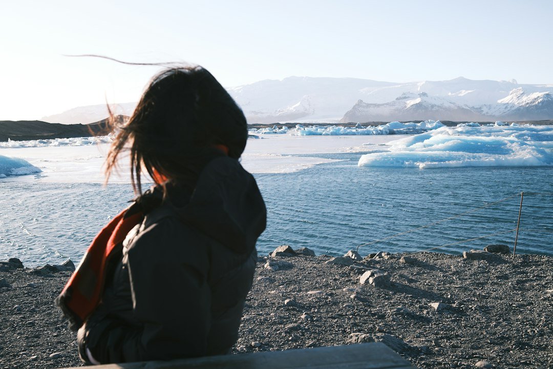 Woman looking across an Arctic glacial lagoon in Greenland