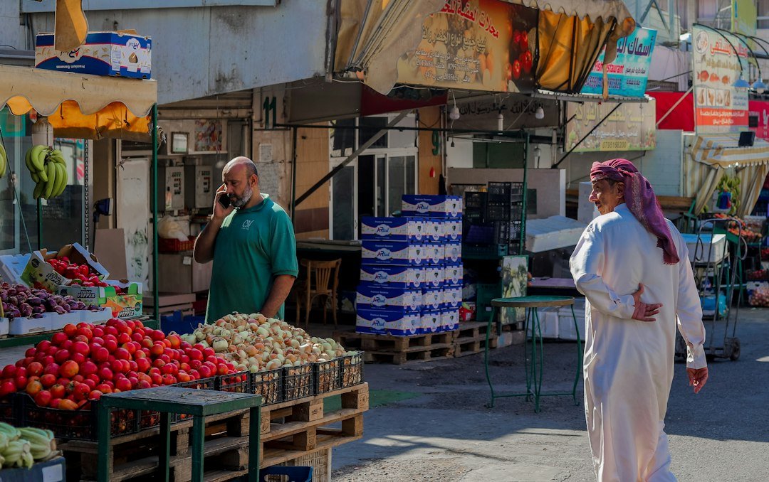 A woman and man walking beside a fruit market in the Middle East